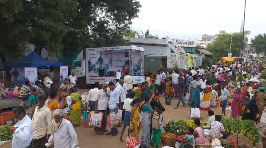 Brand activation van surrounded by shoppers at a village weekly market